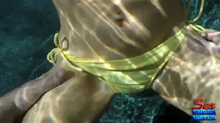 A female in a swimsuit masturbates under water